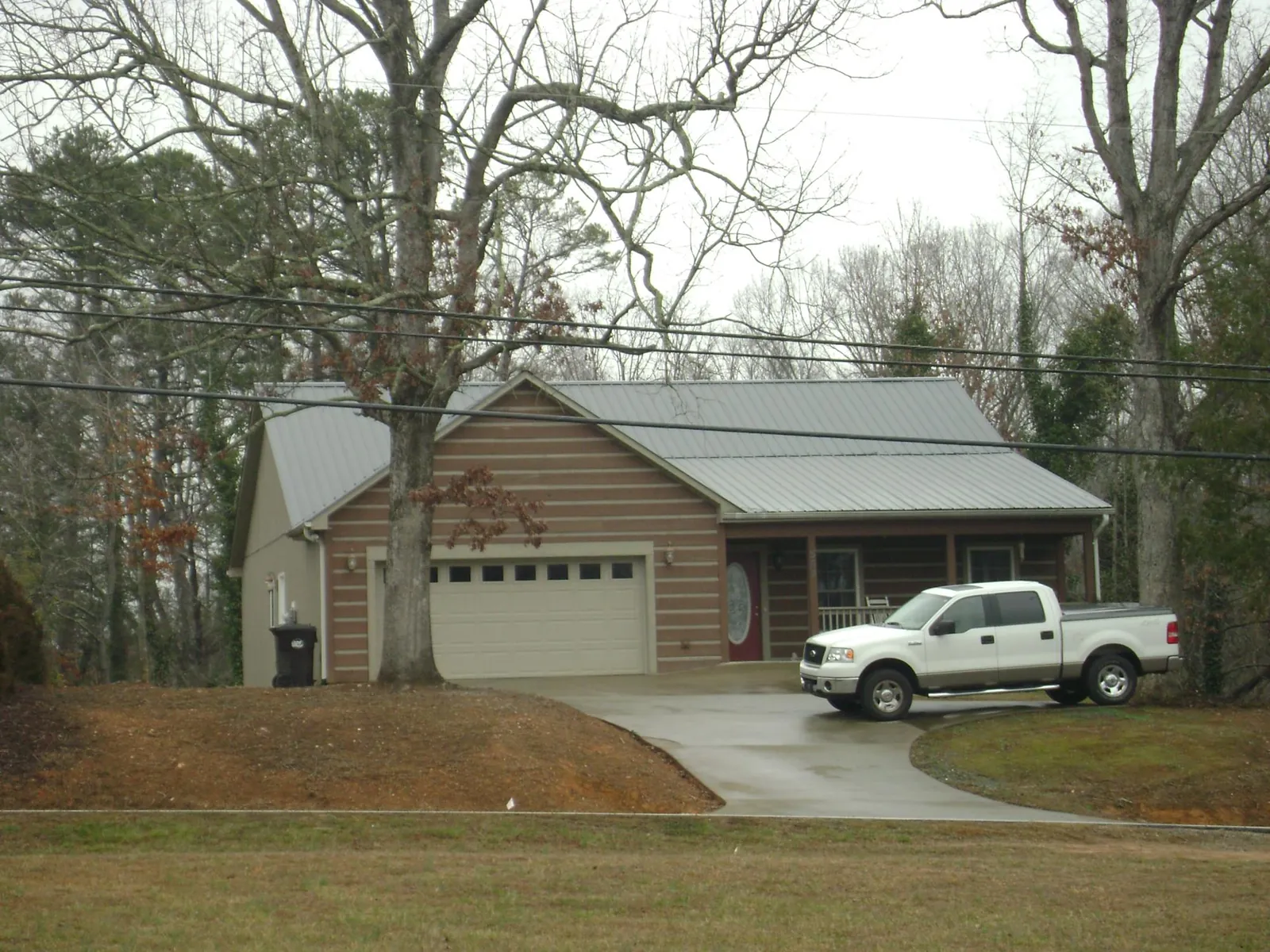 Gray metal roof on a log sided house with an attached two car garage in West Point