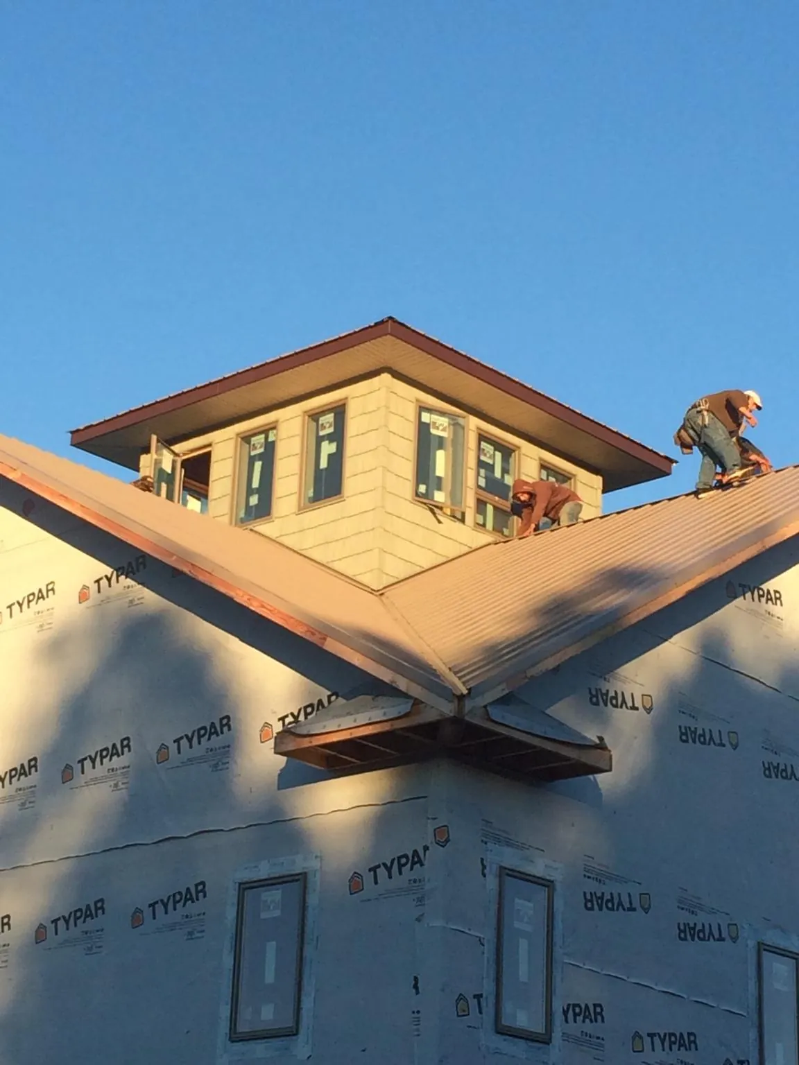 Roofers working around a rooftop cupola on a new metal roof at sunset — Roof Waterproofing in West Point by Roofing Brothers